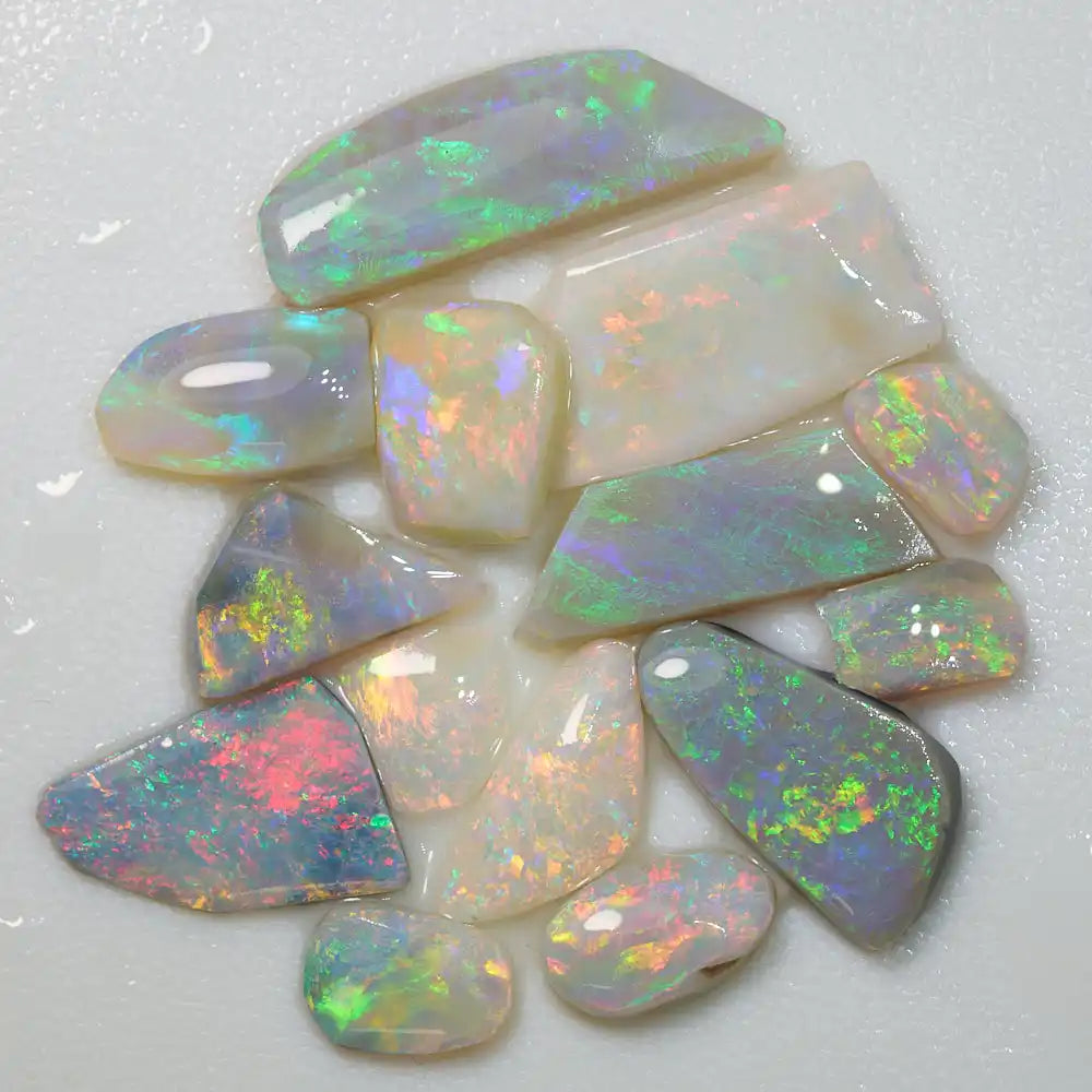 Collection of 14 natural rough opal rubs showcasing vibrant red and multi-coloured hues from Lightning Ridge.