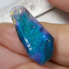 6.06 cts rough black opal rub from Lightning Ridge with vibrant blue and green colors, held between fingers.