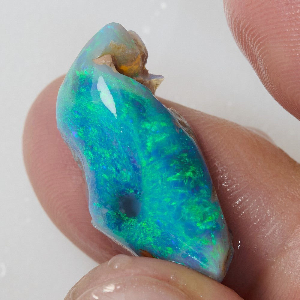 Close-up of a green rough opal rub showcasing vibrant blue and green hues, 