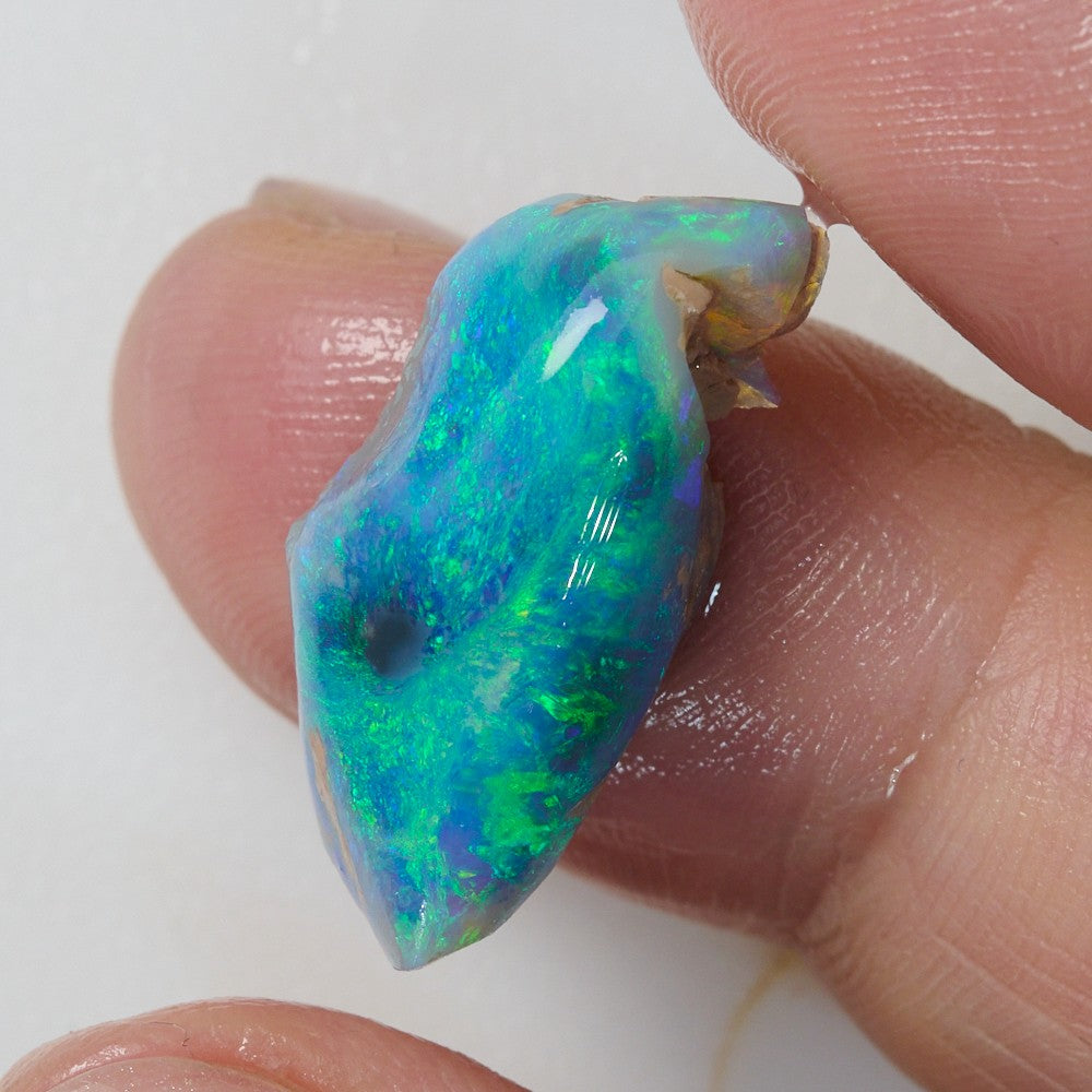 Close-up of a green rough opal rub showcasing vibrant blue and green hues, 