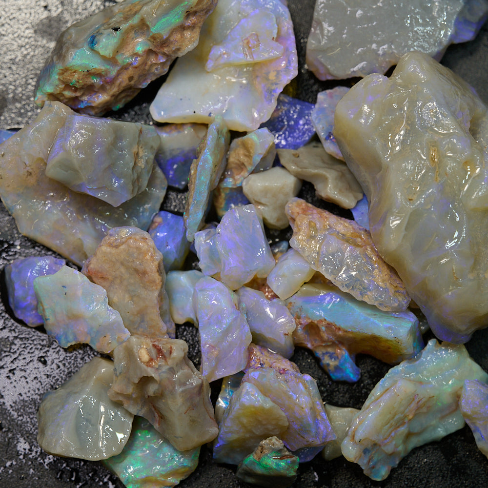 Rough opal gemstones in various sizes showcasing purple and green hues.