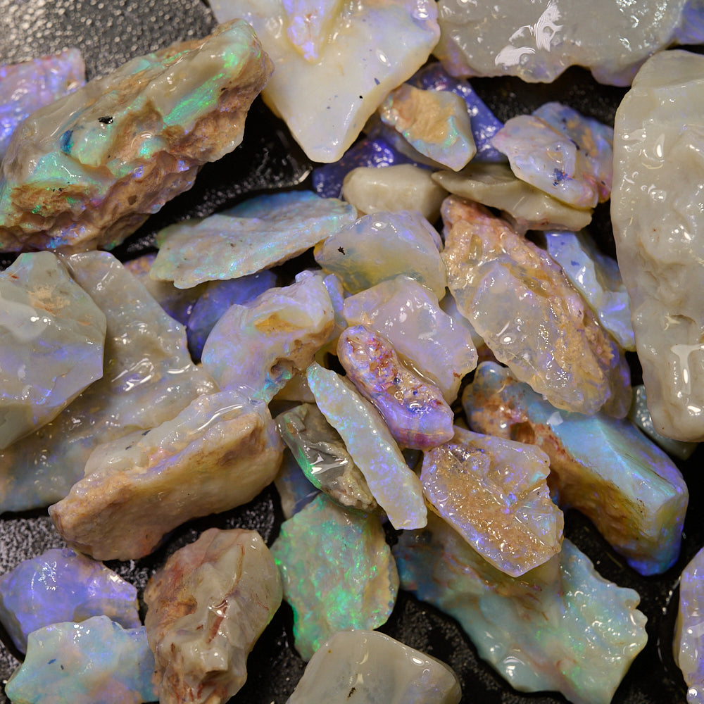 Rough opal gemstones in various sizes showcasing purple and green hues.
