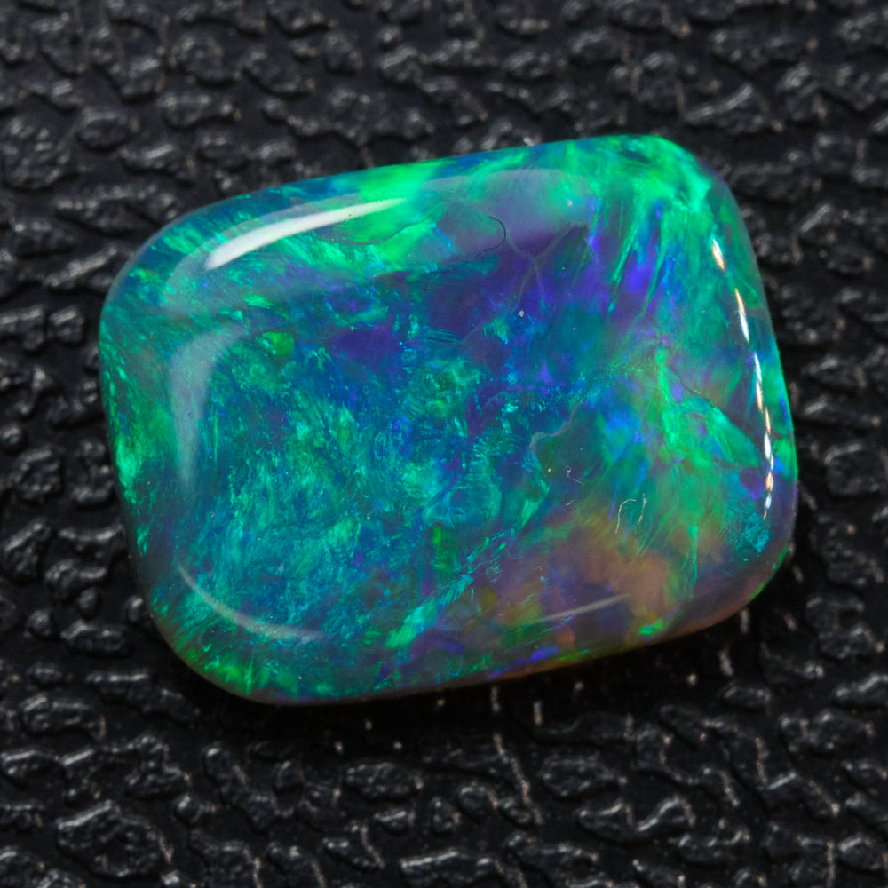 Vibrant 0.90 cts black opal crystal showing green and blue hues, cabochon shape from Lightning Ridge.